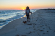Traveler with a dog walks along the surf line